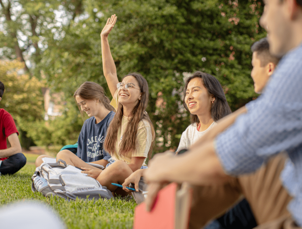 Students sitting outside on the grass.